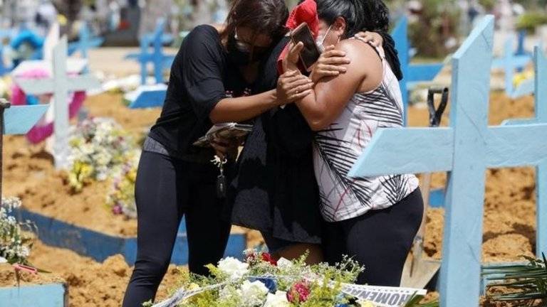 Pessoas abraçadas choram a morte de um familiar